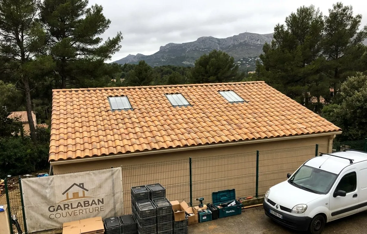 Toiture en tuiles canal terminée par Garlaban Couverture à Aubagne, bâche de l'entreprise sur la clôture et massif du Garlaban au fond